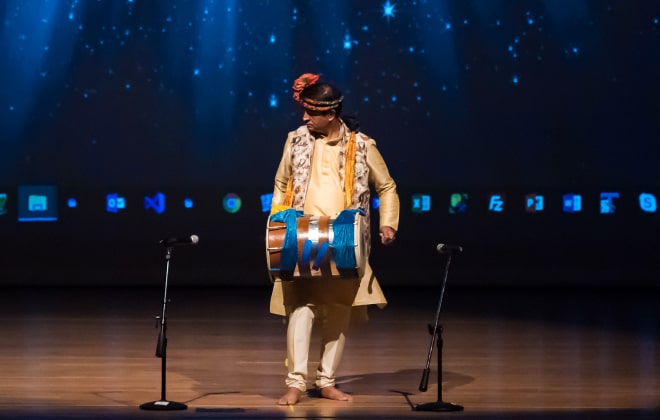 A man playing the Dhol on stage.