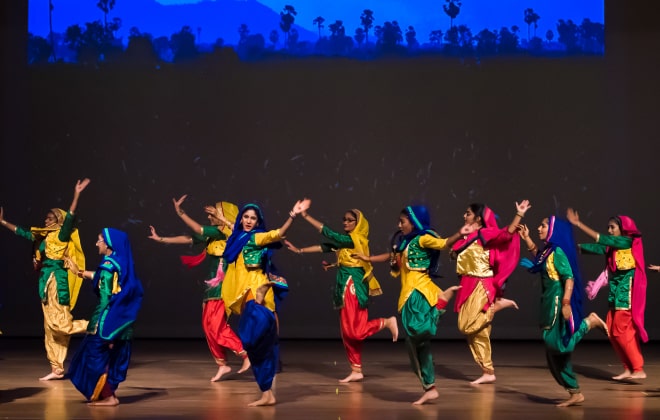 Students performing Bhangra amidst a background of nature. 