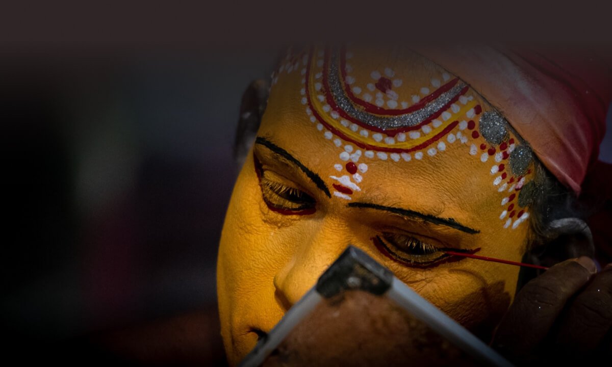 Artist applying intricate makeup for a folk dance performance.