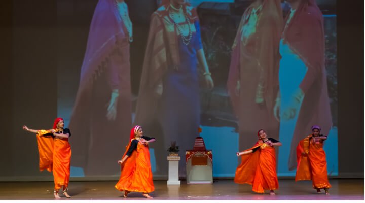 NSDA students wearing colorful attire on stage.