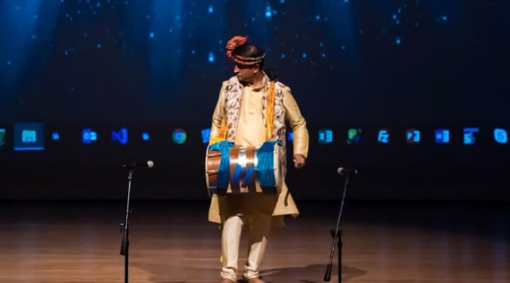 A man playing the Dhol on stage.