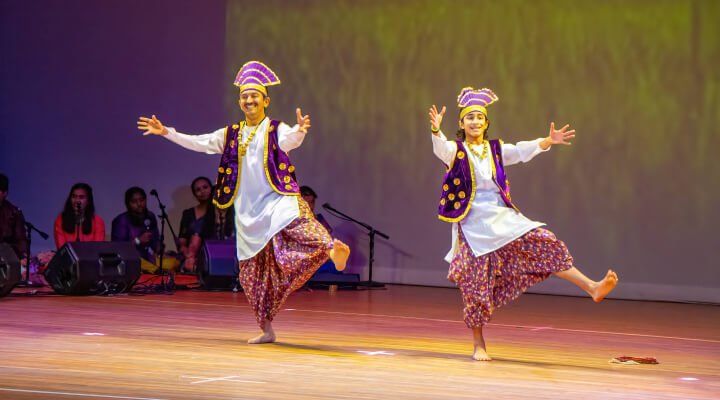 Father and son duo performing bhangra on stage.