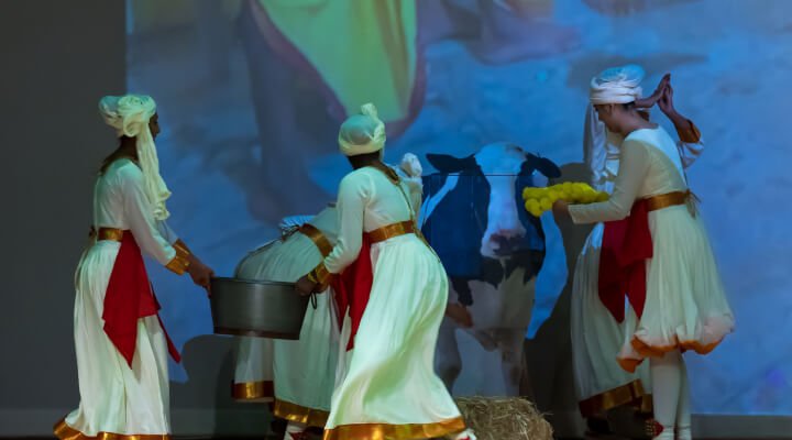 Student carrying a container vessel as a prop on the stage.