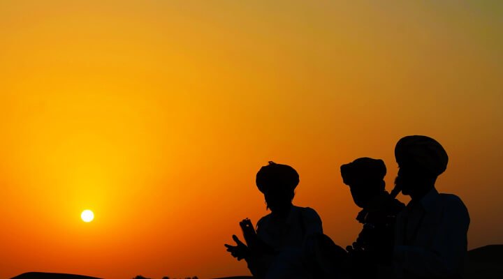 Silhouette of people playing instruments in a desert.