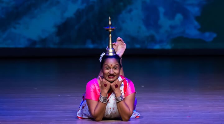 NSDA student balancing a lamp on her head while performing on stage.